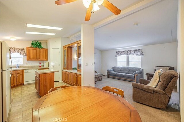dining area with lofted ceiling with beams, light tile patterned floors, a wealth of natural light, and ceiling fan