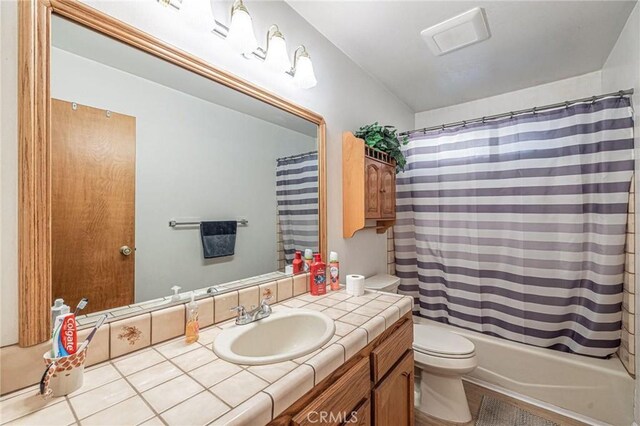 bathroom with shower / bath combo, toilet, vanity, and tile patterned floors