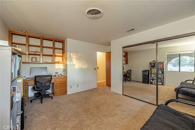 carpeted home office with a textured ceiling and visible vents