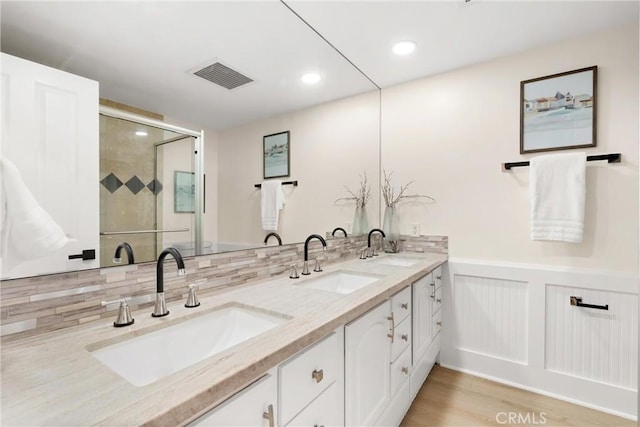 bathroom with visible vents, a sink, and a stall shower