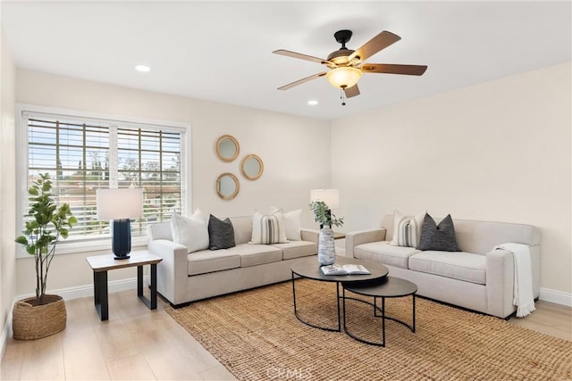 living room with baseboards, light wood-style floors, and ceiling fan