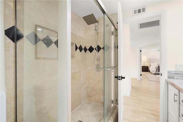 bathroom featuring a shower stall, vanity, wood finished floors, and visible vents