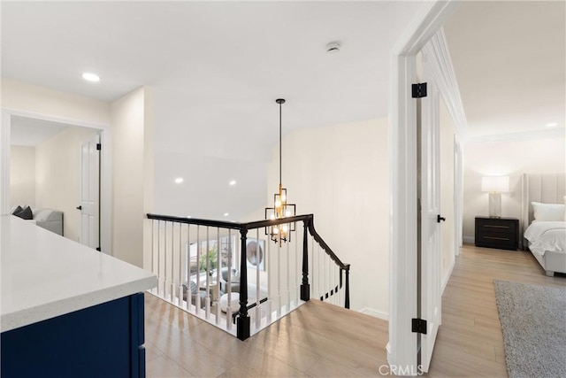 hall with recessed lighting, an upstairs landing, and light wood-style floors