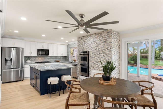 kitchen featuring white cabinets, stainless steel appliances, a kitchen island, and ornamental molding
