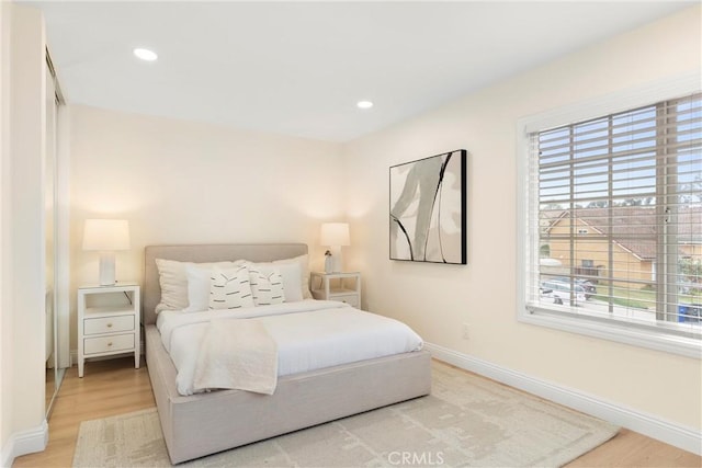 bedroom with wood finished floors, baseboards, and multiple windows