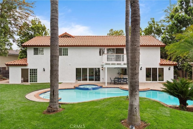 back of house featuring a balcony, a yard, stucco siding, a tile roof, and a patio