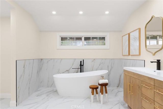 full bathroom featuring a soaking tub, recessed lighting, lofted ceiling, marble finish floor, and vanity