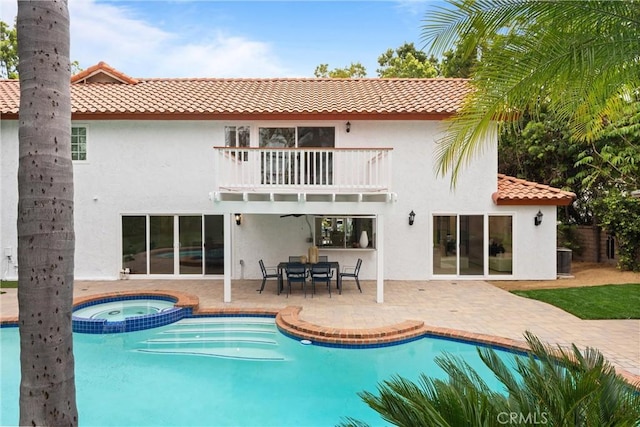 rear view of property featuring a tile roof, cooling unit, a balcony, a patio, and stucco siding