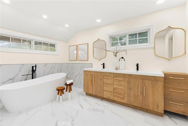 bathroom featuring marble finish floor, a soaking tub, double vanity, and recessed lighting