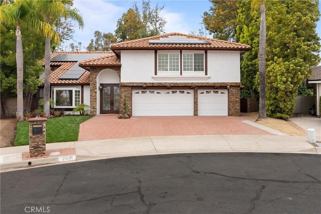 mediterranean / spanish home with roof mounted solar panels, a tile roof, and stucco siding