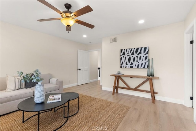 living area featuring visible vents, light wood-style flooring, baseboards, and a ceiling fan