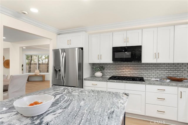 kitchen featuring black appliances, light stone counters, and tasteful backsplash
