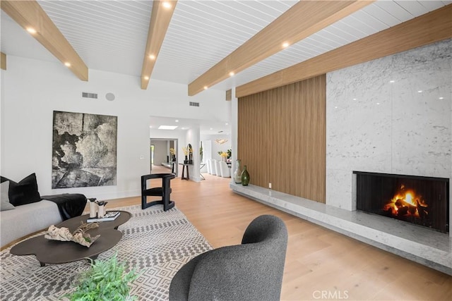 interior space featuring visible vents, wood finished floors, beamed ceiling, and a premium fireplace