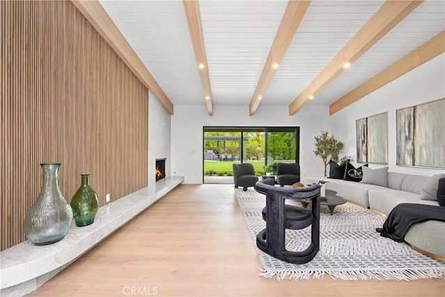 living room with beamed ceiling, baseboards, wood finished floors, and a fireplace