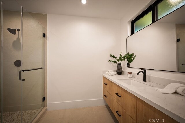 full bath with baseboards, vanity, tile patterned floors, and a stall shower