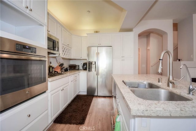 803 Maplewood, Irvine, CA 92618 - kitchen with arched walkways, a sink, white cabinetry, wood finished floors, and appliances with stainless steel finishes