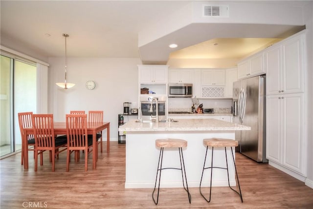 803 Maplewood, Irvine, CA 92618 - kitchen featuring stainless steel appliances, visible vents, light wood-style floors, and white cabinetry