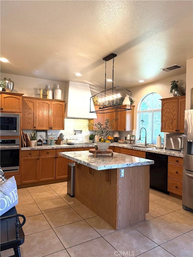 5170 Coronado St, Chowchilla, CA 93610 - kitchen featuring brown cabinetry, a kitchen island, a sink, light tile patterned floors, and stainless steel appliances