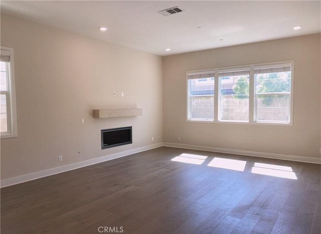 unfurnished living room featuring baseboards, a fireplace, dark wood-style floors, and visible vents