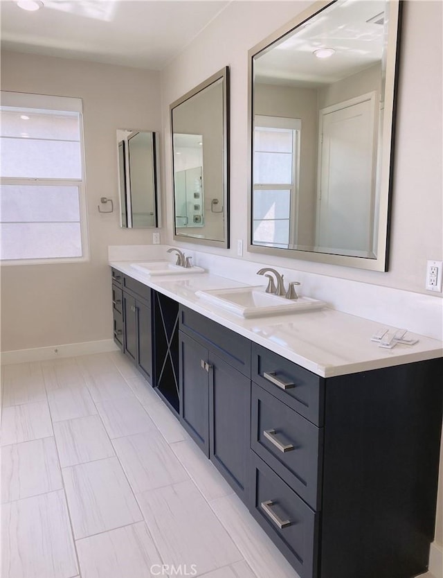 bathroom featuring double vanity, baseboards, and a sink