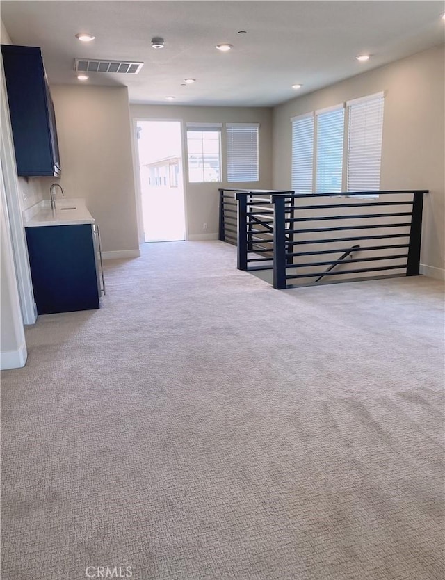 basement with baseboards, light colored carpet, recessed lighting, and visible vents
