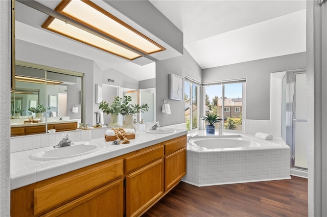 full bathroom featuring lofted ceiling, a garden tub, double vanity, wood finished floors, and a shower stall