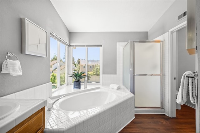 bathroom with vaulted ceiling, a stall shower, wood finished floors, vanity, and a bath