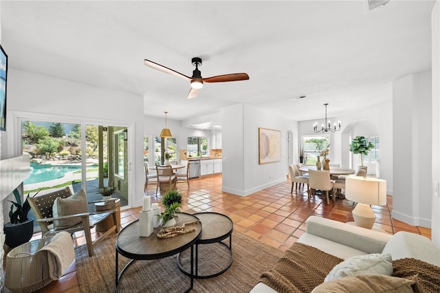 living area featuring healthy amount of natural light, a chandelier, light tile patterned flooring, and baseboards