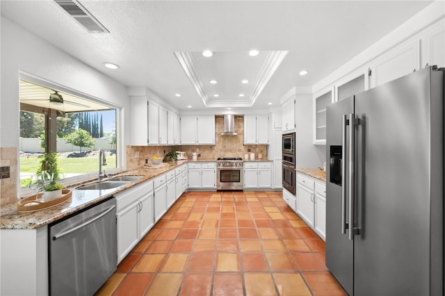 kitchen with high end appliances, a sink, wall chimney exhaust hood, backsplash, and recessed lighting