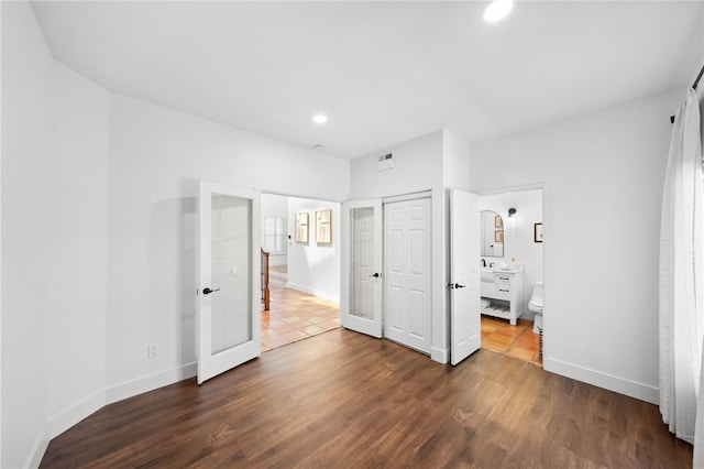 unfurnished bedroom with french doors, baseboards, dark wood-style flooring, recessed lighting, and ensuite bathroom