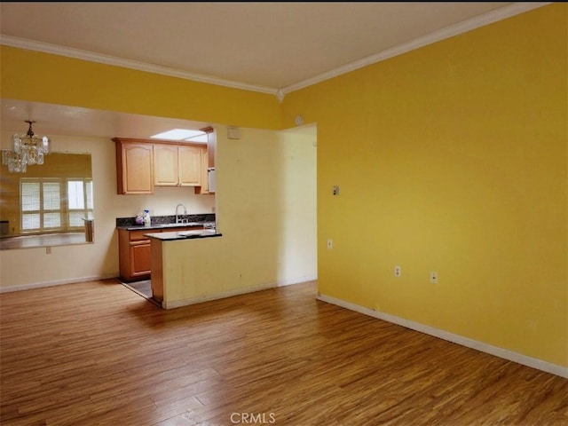 kitchen featuring dark countertops, ornamental molding, light wood-type flooring, baseboards, and a chandelier