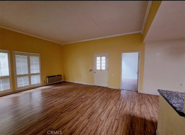 unfurnished living room featuring baseboards, crown molding, and wood finished floors