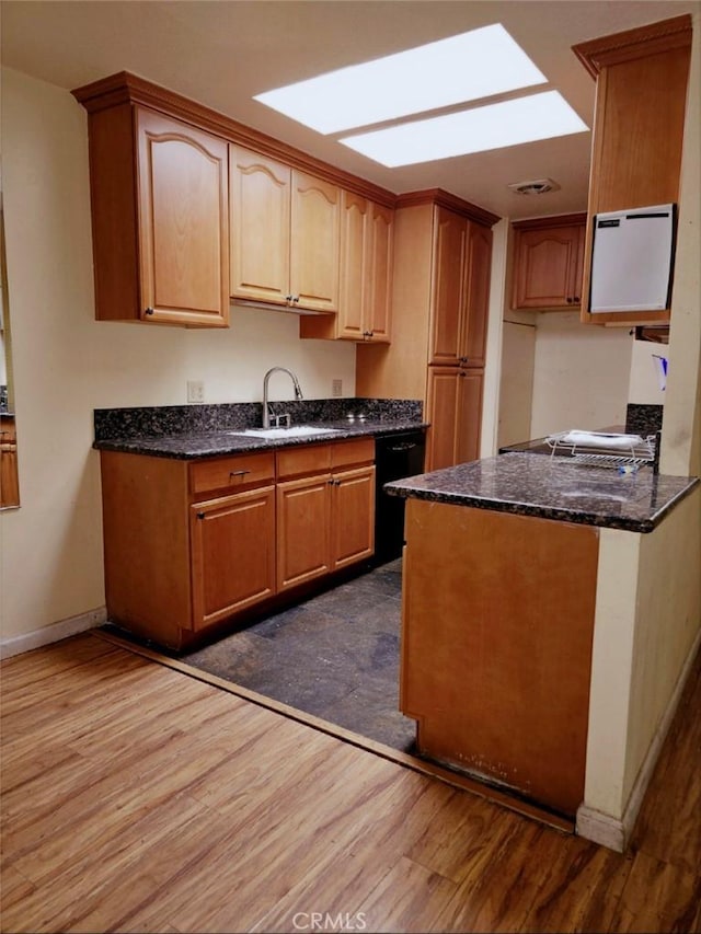kitchen featuring dark stone counters, a sink, baseboards, a peninsula, and dark wood-type flooring