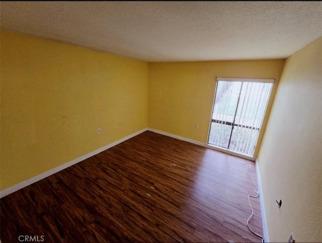 unfurnished room featuring baseboards, dark wood-style floors, and a textured ceiling