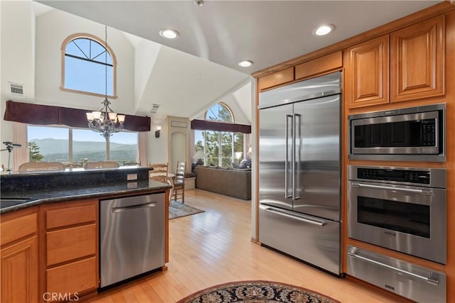 kitchen with visible vents, a warming drawer, light wood-type flooring, built in appliances, and a notable chandelier