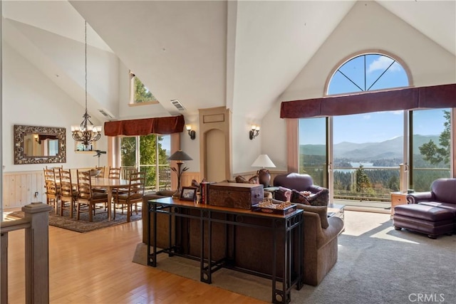 living area featuring high vaulted ceiling, wood finished floors, a chandelier, a mountain view, and visible vents