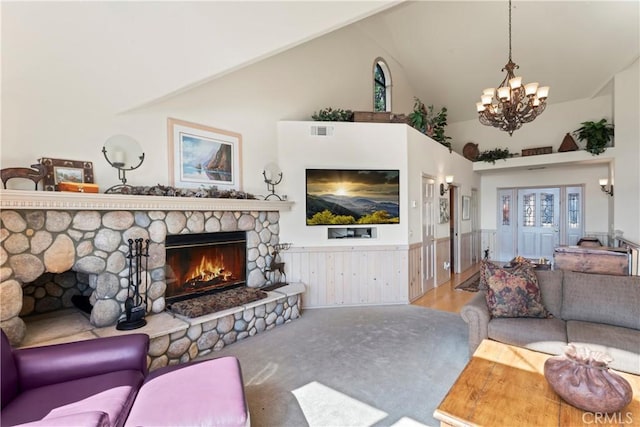 living room featuring an inviting chandelier, a fireplace, high vaulted ceiling, a wainscoted wall, and visible vents