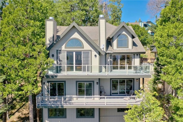 back of property with a chimney and a balcony