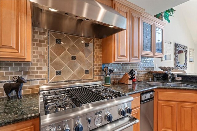 kitchen featuring wall chimney exhaust hood, stainless steel range, a sink, and backsplash