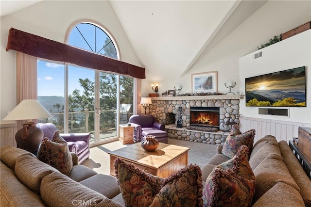 living area with a fireplace, visible vents, high vaulted ceiling, and wainscoting