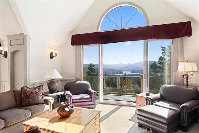 living area with wainscoting, vaulted ceiling, and a mountain view