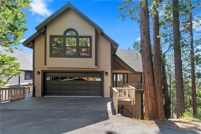 rustic home with driveway, a shingled roof, and a garage