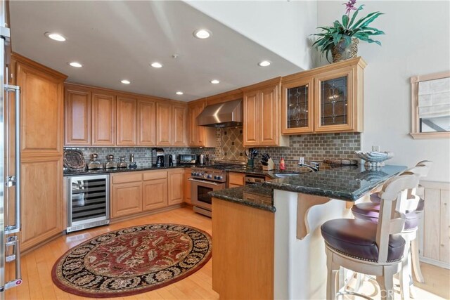 432 Grizzly Rd, Lake Arrowhead, CA 92352 - kitchen featuring wine cooler, wall chimney range hood, stainless steel range, a peninsula, and dark stone countertops