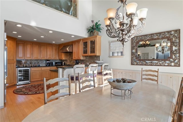 dining area with a notable chandelier, light wood-style floors, wine cooler, and recessed lighting