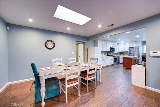 dining space with recessed lighting, visible vents, a skylight, baseboards, and dark wood-style flooring