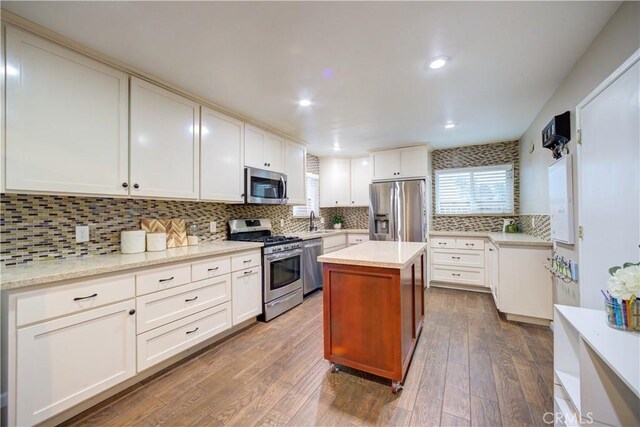 234 N 12th St, Grover Beach, CA 93433 - kitchen with appliances with stainless steel finishes, backsplash, dark wood-style flooring, white cabinetry, and a kitchen island