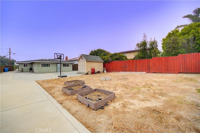 view of yard featuring a vegetable garden, a fenced backyard, a shed, a patio area, and an outdoor structure