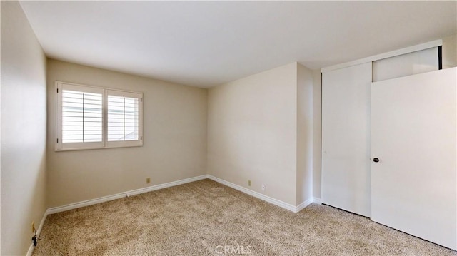 spare room featuring carpet floors and baseboards