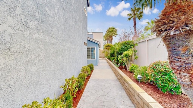 view of side of home with stucco siding and fence