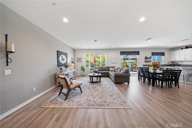 living room featuring light wood-style floors, baseboards, recessed lighting, and visible vents